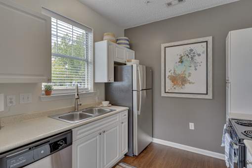 A kitchen with a refrigerator, sink, and cabinets.