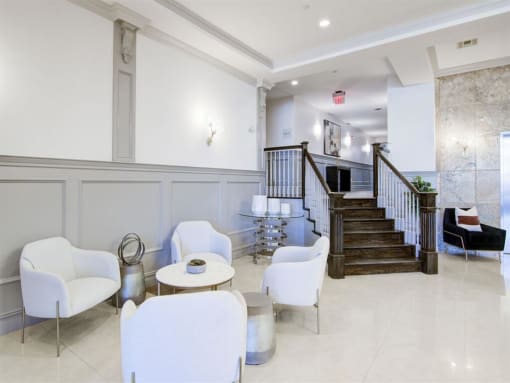 a lobby with white chairs and a staircase in the background