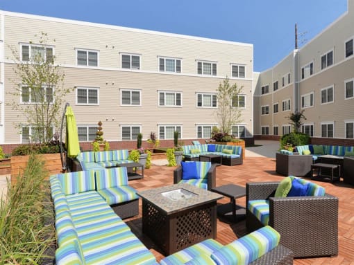 a patio with couches and tables in front of an apartment building