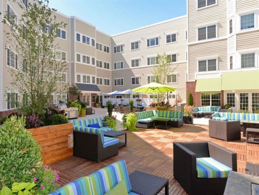 an outdoor lounge area with a yellow umbrella and apartment buildings in the background