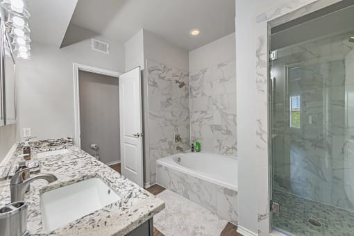 A bathroom with a marble countertop and a walk-in shower and soaking tub at Barton Creek Villas, Austin, TX