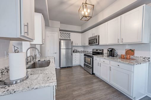 A kitchen with white cabinets and a marble countertop. at Barton Creek Villas, Austin, TX