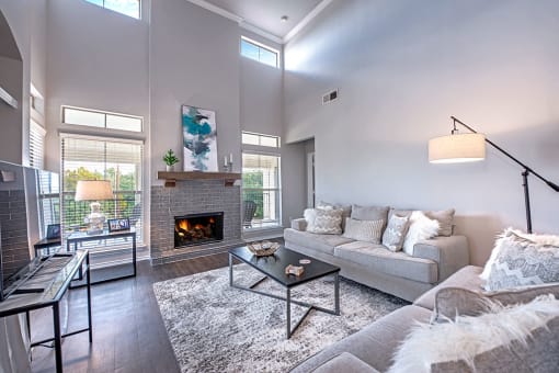 A modern living room with a grey couch, a fireplace, and a glass coffee table. at Barton Creek Villas, Texas, 78735