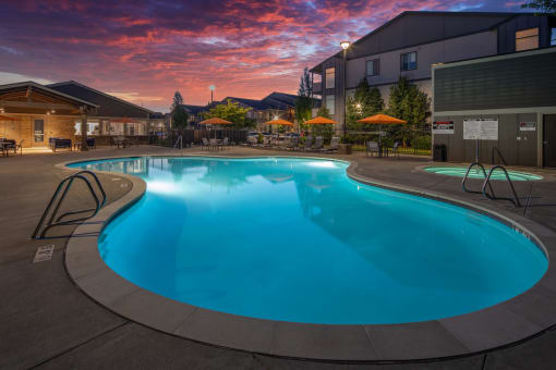 a swimming pool at dusk at a hotel with a sunset in the background