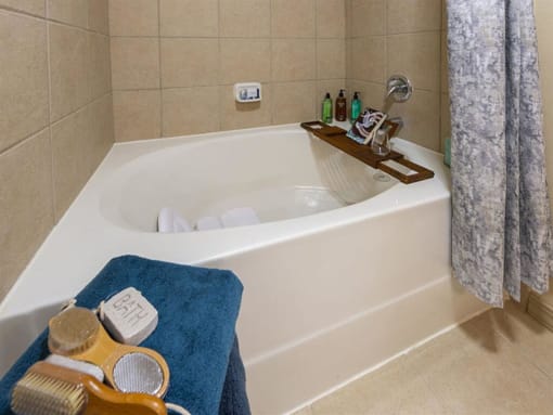 a bathtub with a wooden tray on top of it at Retreat at Shadow Creek Ranch Apartments, Woodburn, 77584