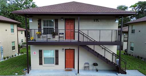 the front of a house with a balcony and two doors