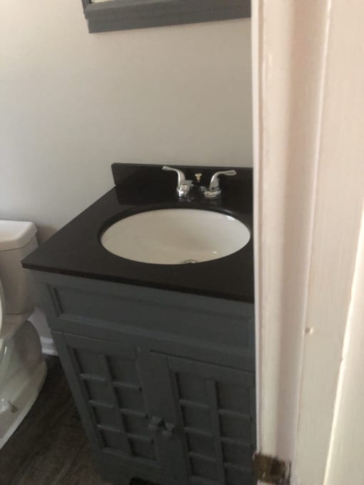 a sink with a black countertop and a silver faucet