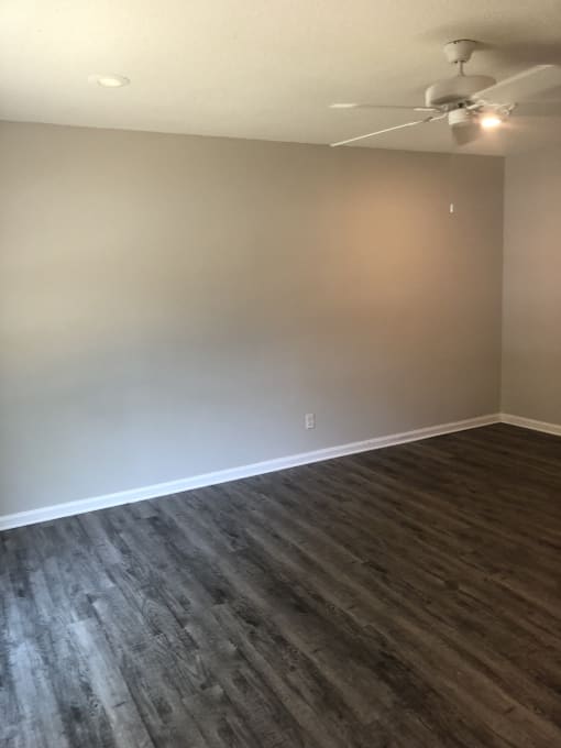 an empty room with a ceiling fan and hardwood floors