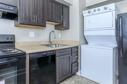 a kitchen with black cabinets and white appliances at Parkland Village, Forestville