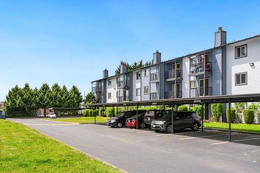 a parking lot with cars in front of an apartment building at Eagles Landing Apartments, Everett, WA 98204