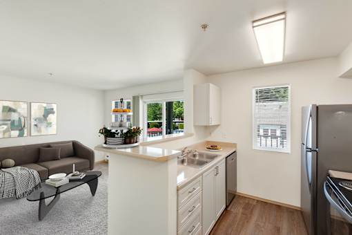 a living room with a couch and a kitchen with a sink at Sage Apartments, Everett, Washington