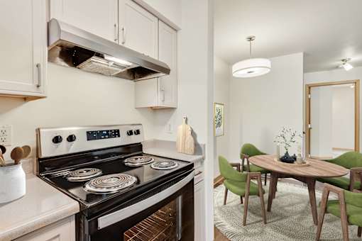 a kitchen with a stove and a dining room with a table and chairs at Sage Apartments, Washington, 98204