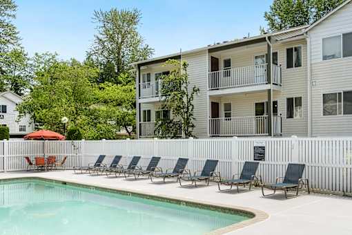 a swimming pool with chairs in front of a house at Sage Apartments, Washington