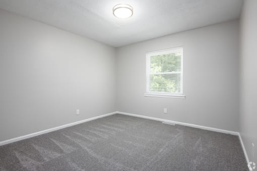 an empty room with carpet and a window