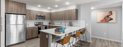 A modern kitchen with a refrigerator, microwave, oven, and a dining table with chairs.