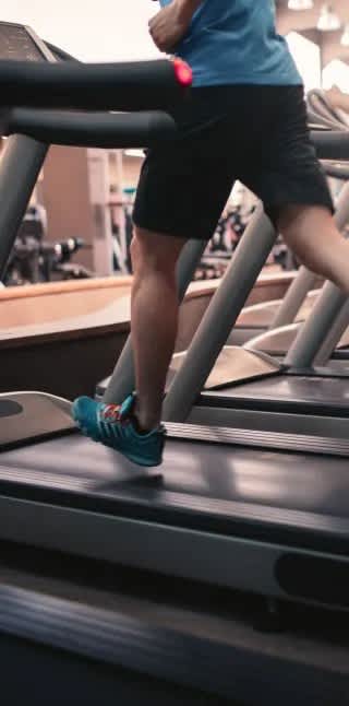 A man is running on a treadmill in a gym.