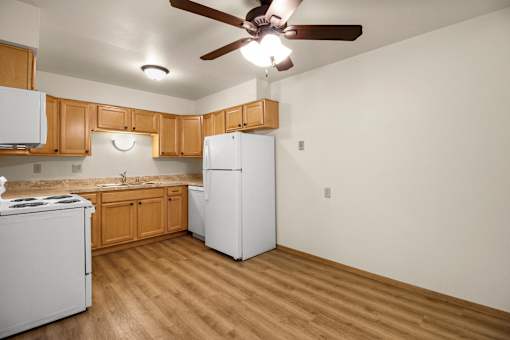 A kitchen with a white refrigerator, white stove, and wooden cabinets.