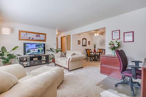 A living room with a white couch, a television, and a chair.