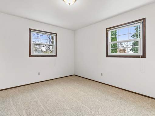 A room with two windows and carpeted floor.