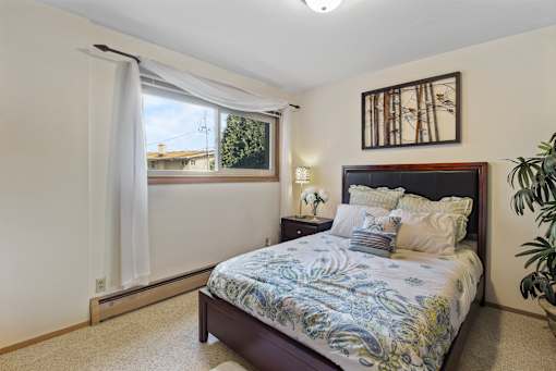 A bedroom with a bed, nightstand, and window.