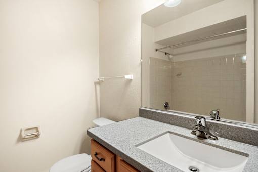 A bathroom with a toilet, sink, and mirror.