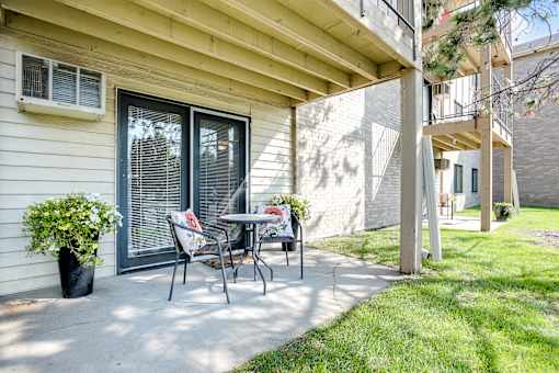 A patio with a table and chairs is in front of a house.