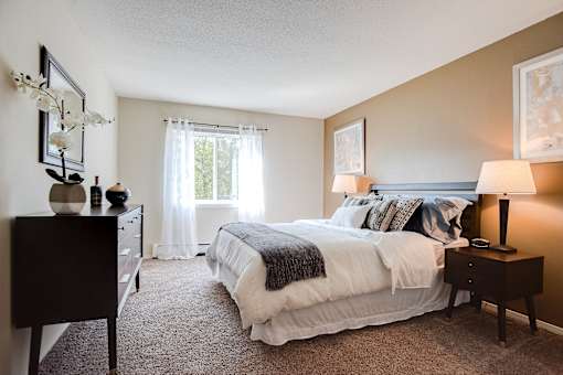 A bedroom with a bed, nightstand, and a dresser.