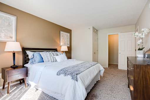 A bedroom with a large bed and a nightstand with a lamp.