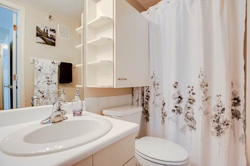 A white bathroom with a floral shower curtain.