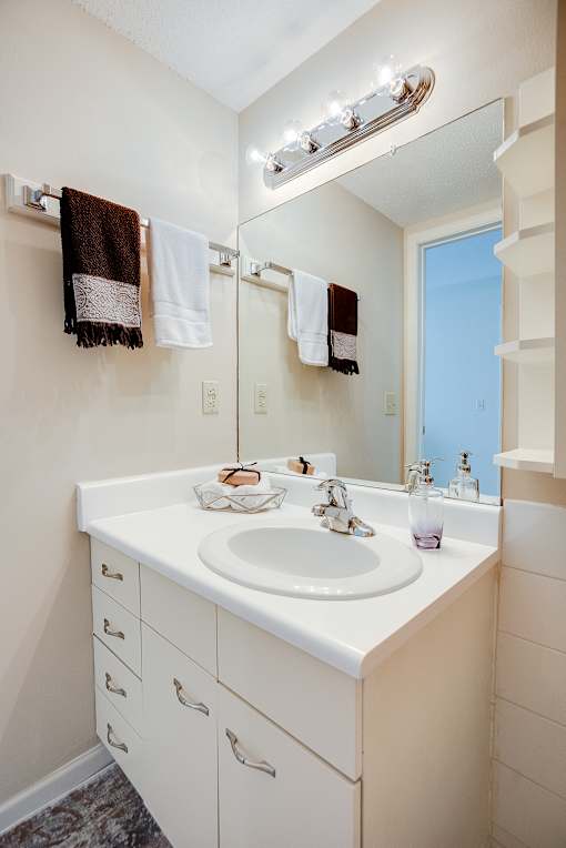 A white bathroom with a sink and mirror.