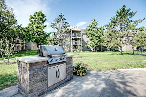 A stone grill is in the foreground of a residential area.