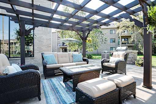 A patio with a black wicker couch and a white cushion.