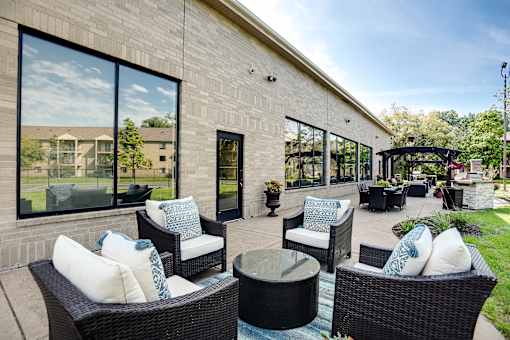 A patio area with wicker furniture and a glass table.