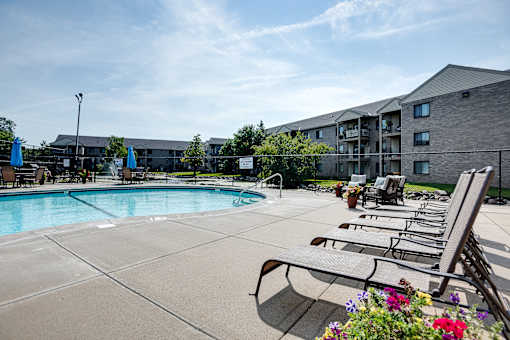A pool area with lounge chairs and a building in the background.