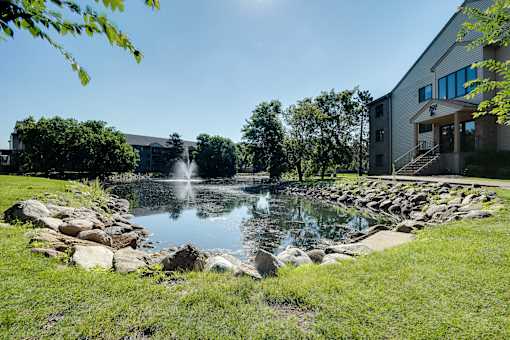A fountain in the middle of a grassy area with a building in the background.