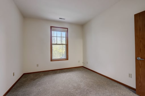an empty room with white walls and a window