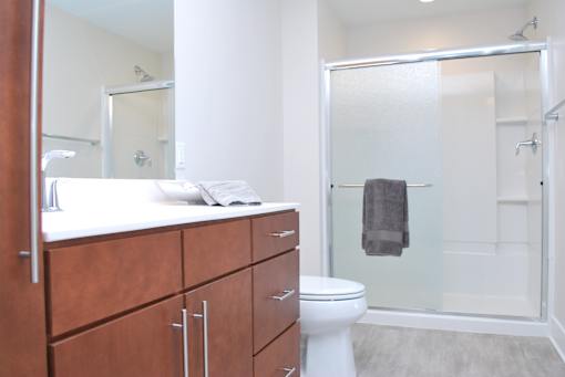 A white toilet sits in a bathroom with a walk-in shower.
