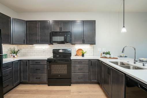 A kitchen with black cabinets and a black oven.