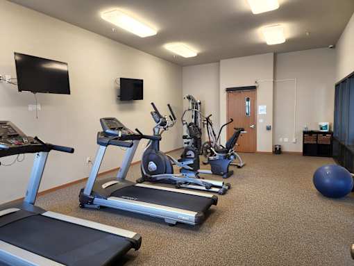A gym with treadmills, exercise bikes, and other equipment.