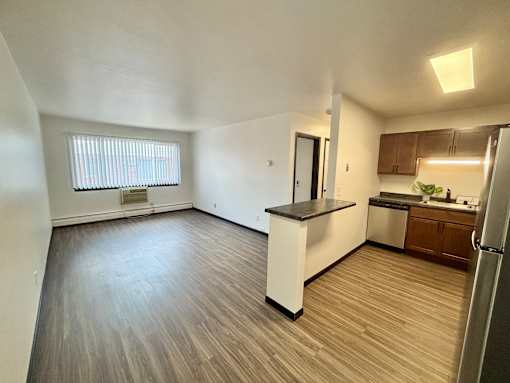 A kitchen with a refrigerator, sink, and cabinets.