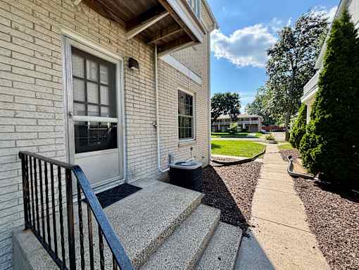 A house with a white door and a black railing on the steps.