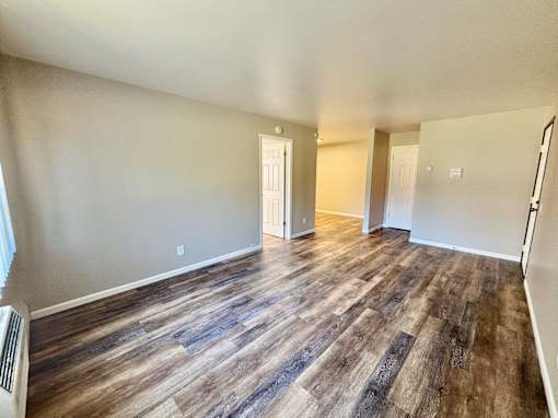 A room with wooden flooring and white walls.