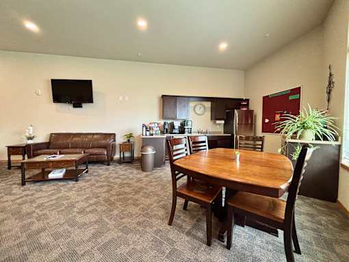 A living room with a brown couch, a wooden table, and a television mounted on the wall.