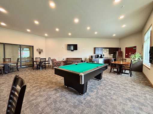 A room with a pool table and chairs.