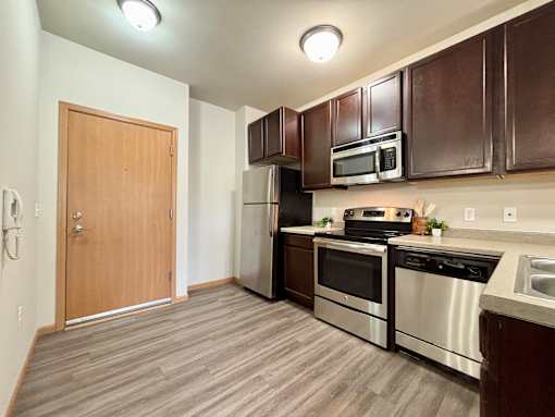 A kitchen with a refrigerator, oven, microwave, and sink.