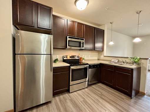 A kitchen with a stainless steel refrigerator, microwave, oven, and sink.