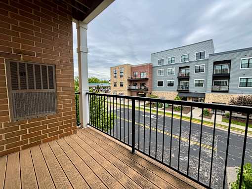 A balcony with a black railing and a brick wall.