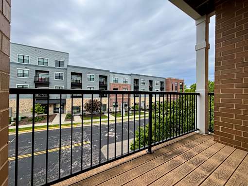 A view of a street from a balcony with a black railing.