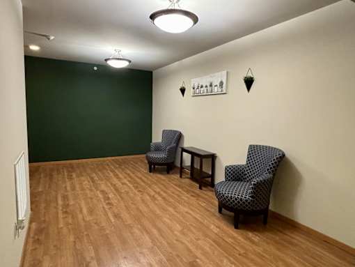 Two chairs and a table are in a room with wooden floors.
