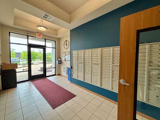 A hallway with a red carpet and a wall of mailboxes.